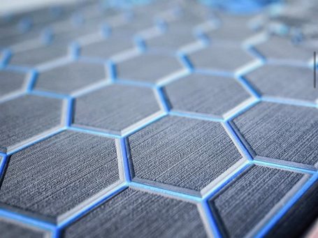 Surface en relief avec un motif de hexagones et des traits bleus.